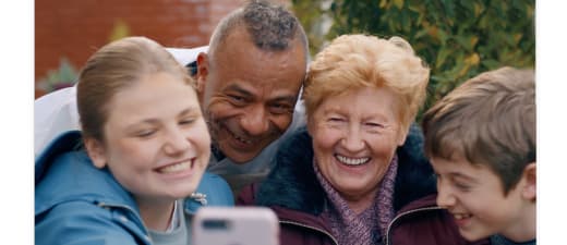 Oma en twee kleinkinderen maken een selfie met een verpleegkundige erbij