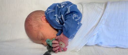 Pasgeboren baby met een pleister op het hand na de bloedprik