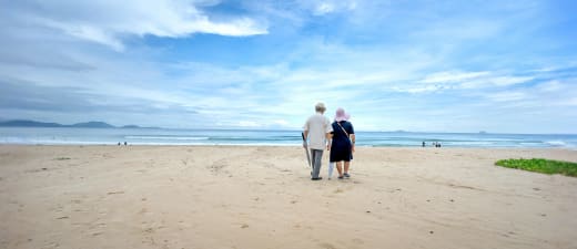 2 oudere mensen wandelen op het strand