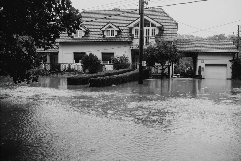 Huis met straat die overstroomd is door noodweer